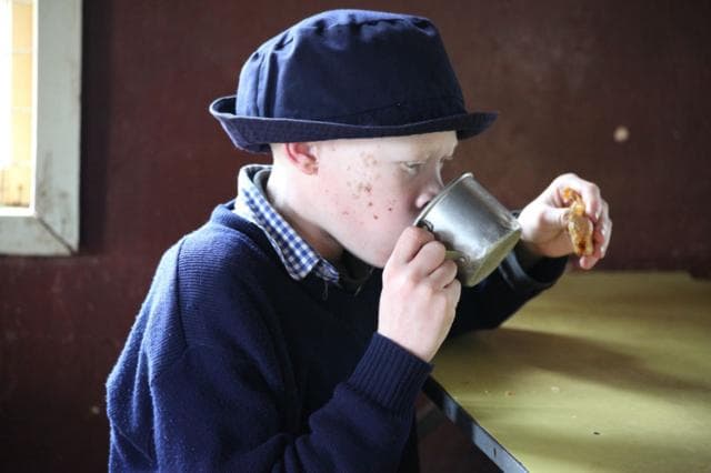 A student in school uniform drinking from a cup