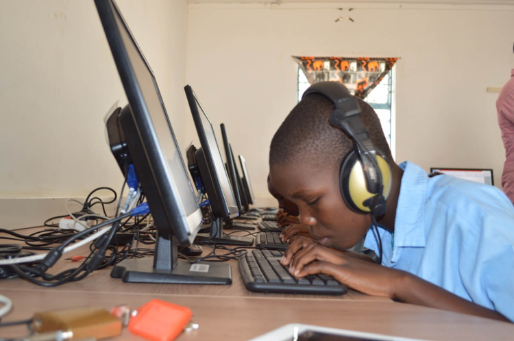 A blind student using a desktop computer wearing headphones inside one of the inABLE Computer Labs for the Blind