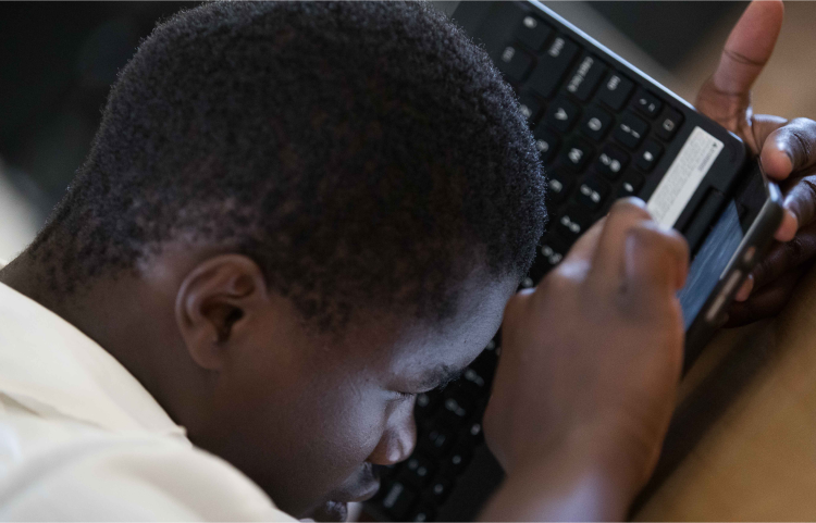 A photo of a student using a Chromebook laptop closely held to his face
