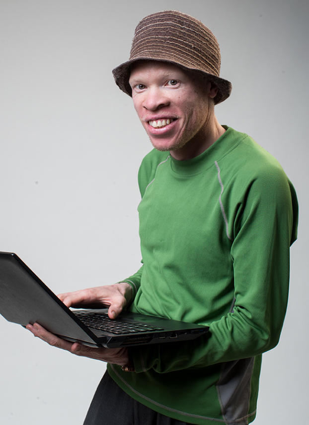 John Brown, inABLE Alumnus holding a laptop and smiling at the camera