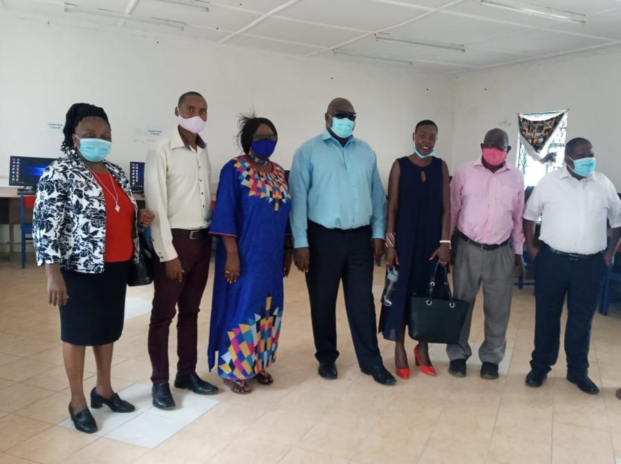 Six Ministry of Education Guests and inABLE Team pose wearing masks in front of computers Assistive Computer Lab for Blind at Likoni School