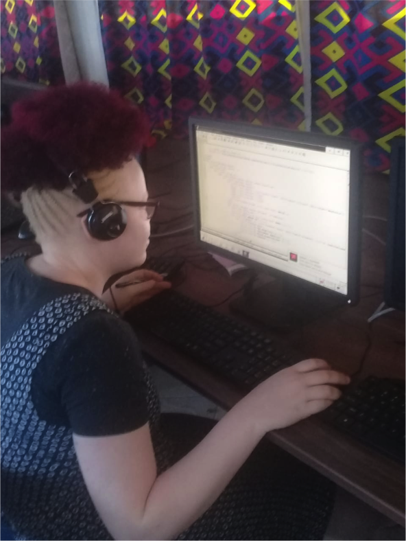 inABLE intern Delvin Obara, who wears glasses due to low vision, looks at her computer screen while learning coding.