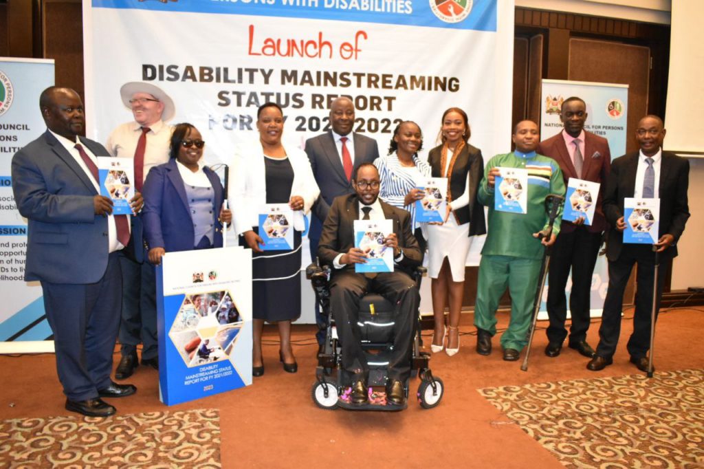 A group picture taken during the Launch of Disability Mainstreaming Status Report. It includes Hon. Florence Bore, Harun M. Hassan, Hon. David Ole Sankok & others holding a copy of the report in their hands.