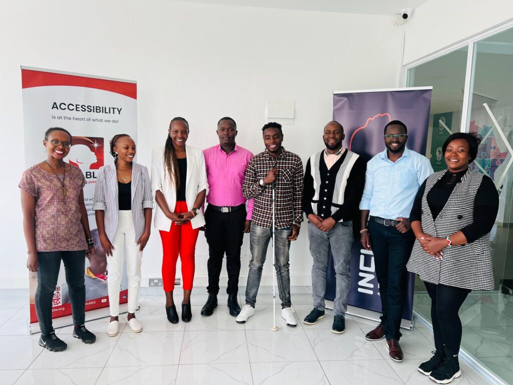 A picture that of the Digital Story Time Team and the inABLE Team smiling and posing for a picture. They're standing in front of an inABLE and Inclusive Africa Conference banner. 