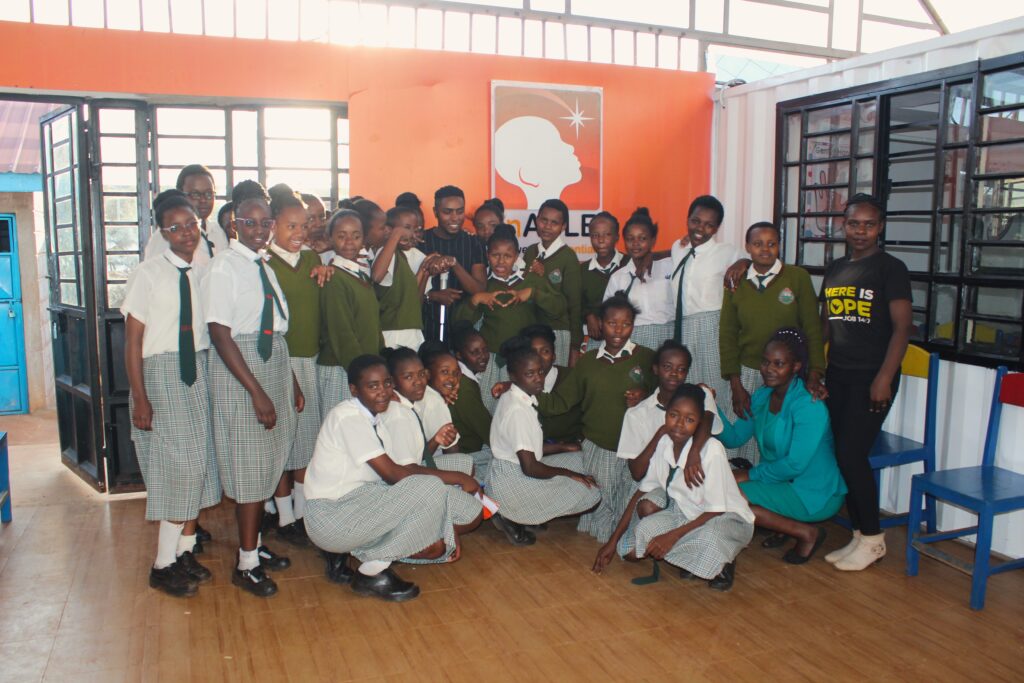 A picture that includes Evelyn Omollo, Julius Mbura, Valary Olesia and high school students smiling and posing for a picture inside Kang'aru Digital Hub.