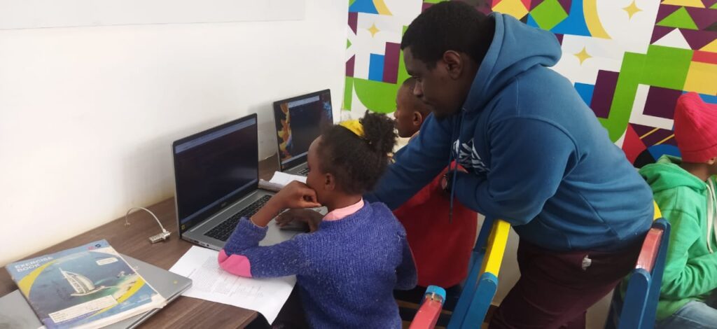 A picture of Kelvin Karanja, a Coding Instructor assisting pupils during a Coding Lesson. 