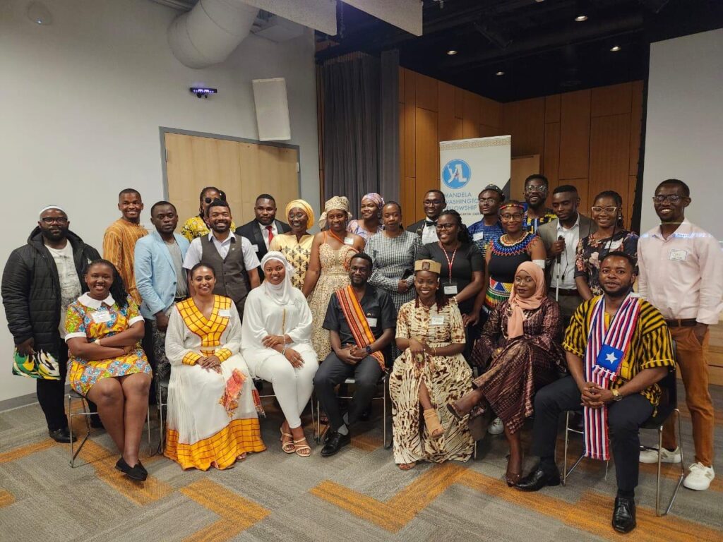 A group picture of Mandela Washington Fellows that includes Julius Mbura, they're all standing and posting for a picture with a Mandela Washington Fellowship banner behind them.