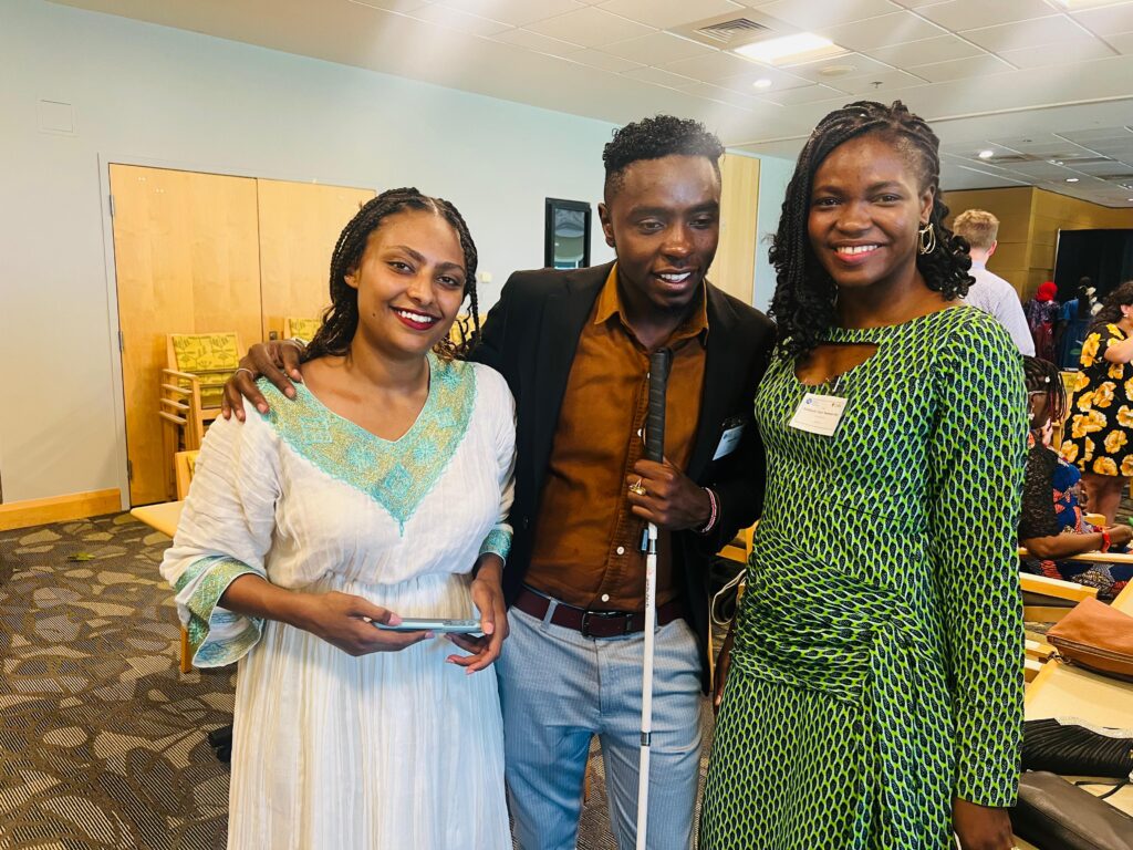 A picture of Julius Mbura and two ladies standing next to him. They're all posing for a photo.