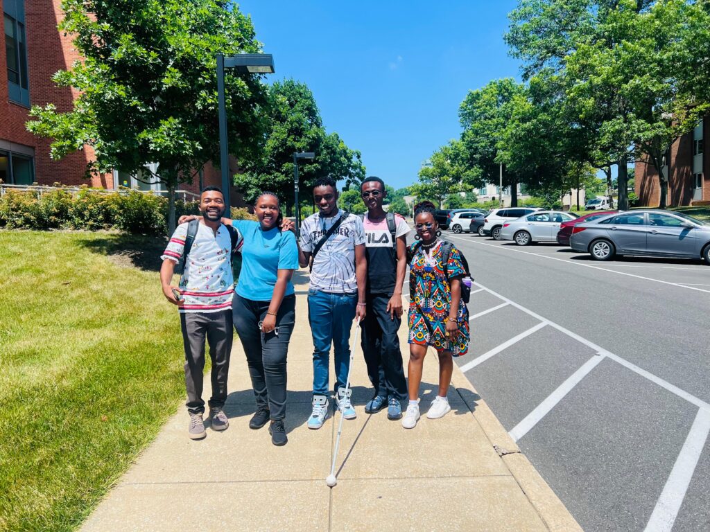 A picture of Julius Mbura and other people smiling and posing for a picture.