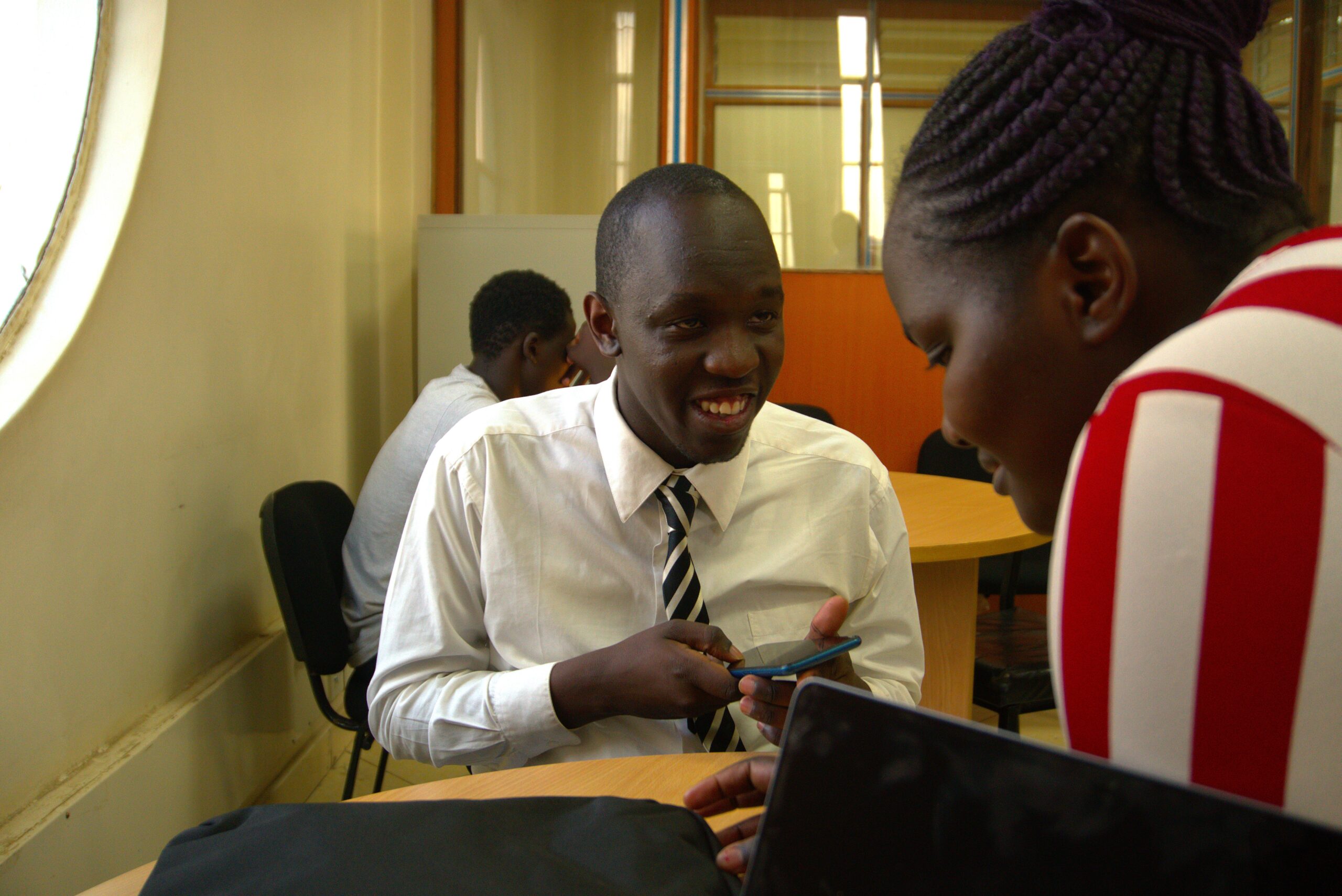 A picture of a John Moses Ominde smiling and talking with a Valary Olesia, an inABLE computer instructor.