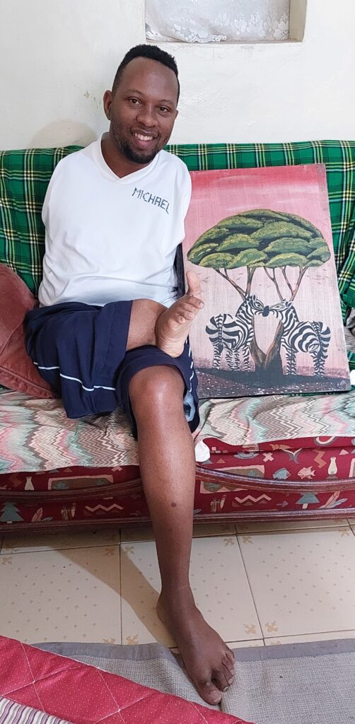 Sammy sits on a couch, with a colorful painting placed near him.